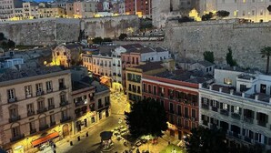 Un paisaje urbano histórico con una imponente muralla de piedra, edificios tradicionales y una plaza central.
