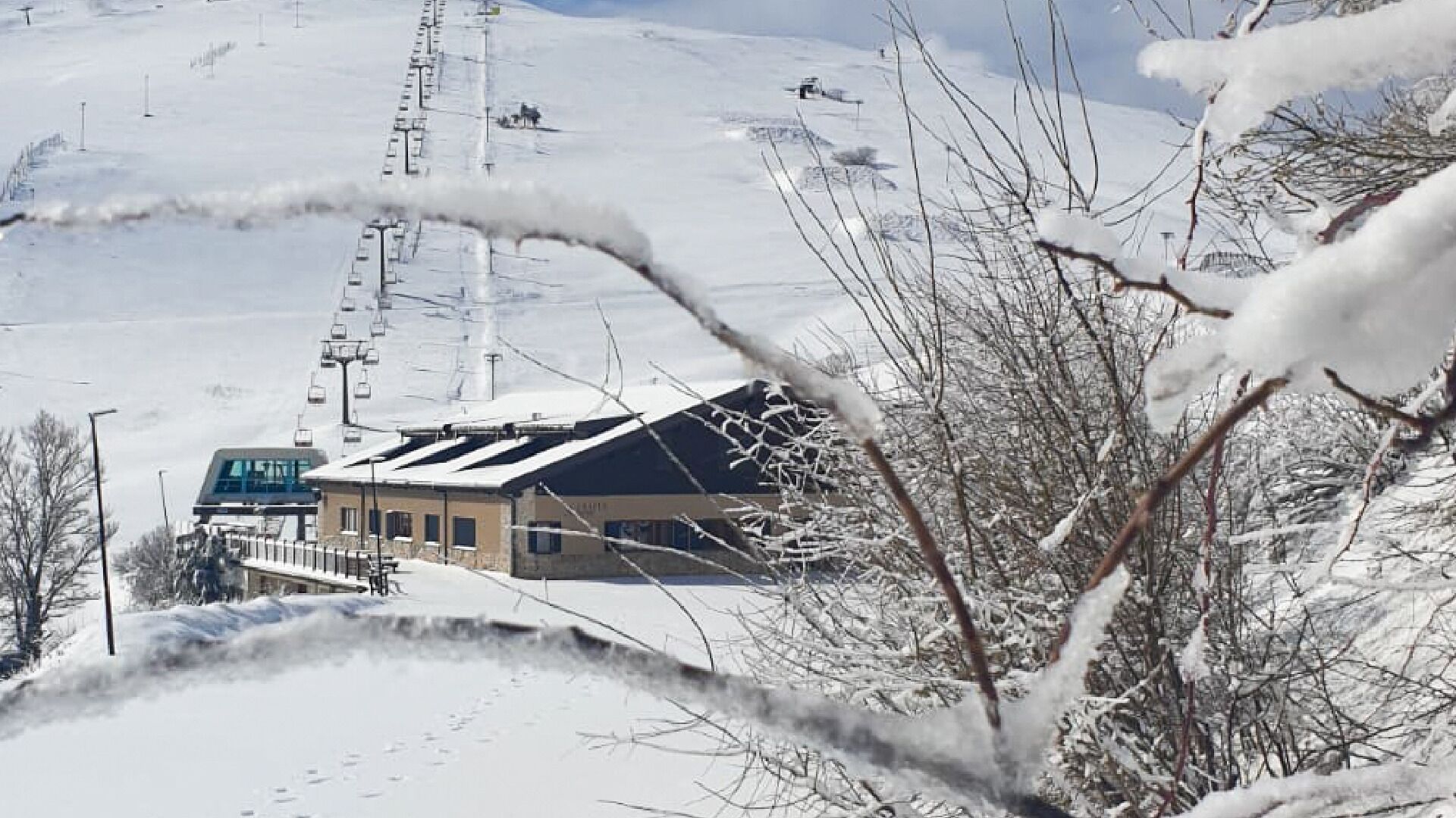 A building with a sloped roof, likely a ski resort or lodge, with a ski lift in the background.