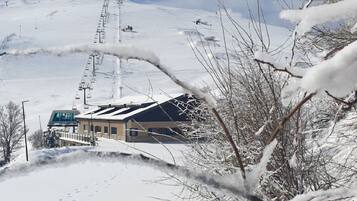 A building with a sloped roof, likely a ski resort or lodge, with a ski lift in the background.