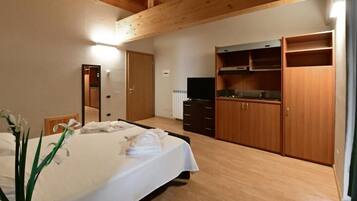 Quarto de hotel com cama, televisão, armários de madeira e banheiro.