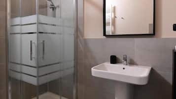 A modern bathroom with a glass shower enclosure, a sink, and a mirror.