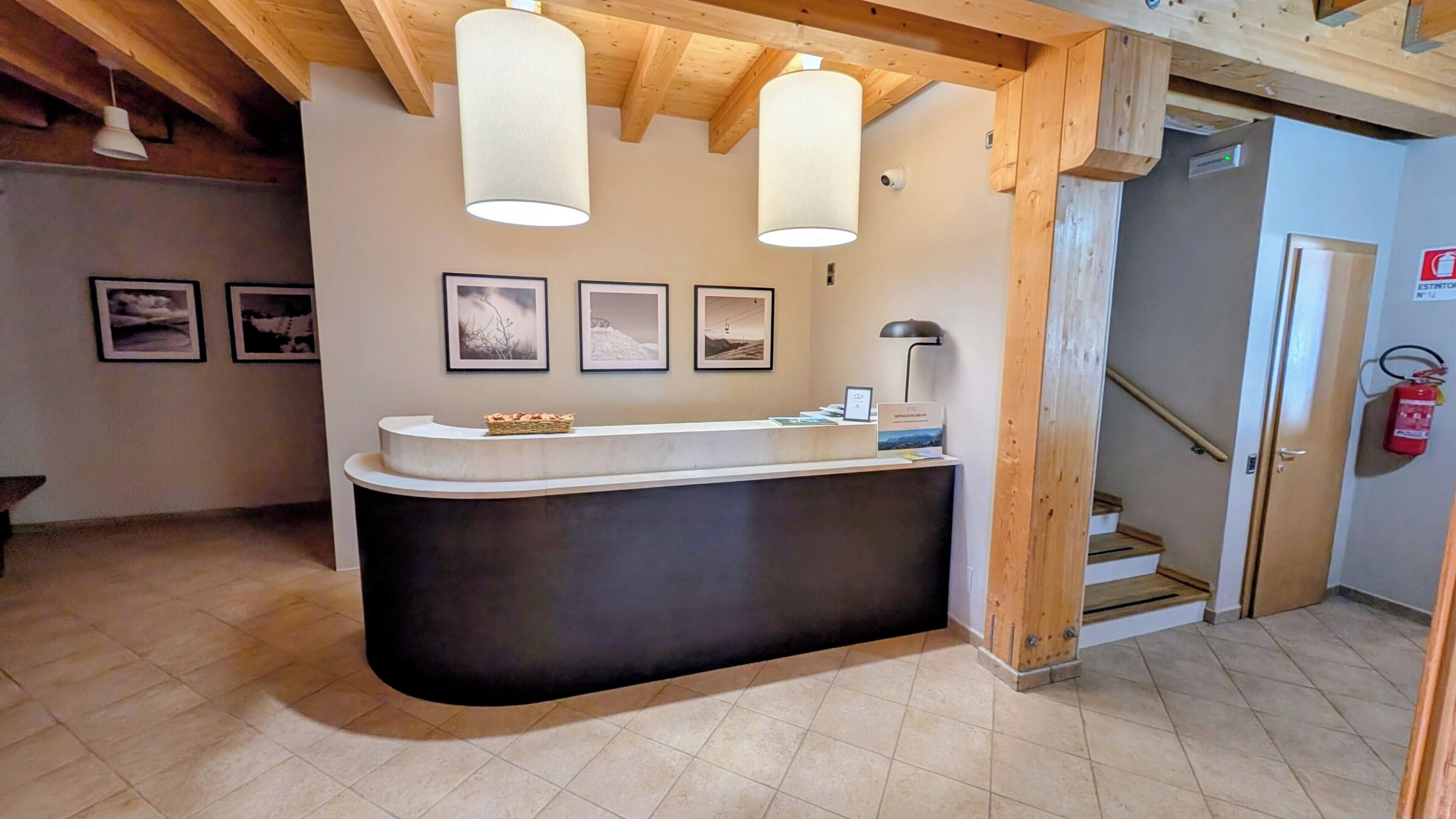 A reception desk with a curved design, a wooden ceiling, and framed pictures on the wall.