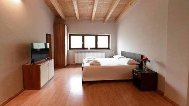 Habitació amb llit, televisió, finestra i radiador.