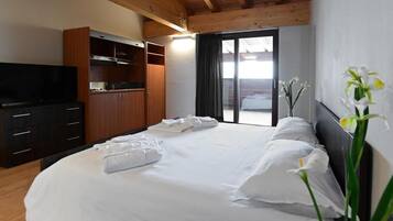 Una camera d'albergo con un letto, una televisione, un armadio e vista sull'esterno.