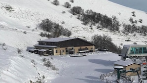 Estació d'esquí amb un gran refugi, seients a l'aire lliure i un paisatge cobert de neu.