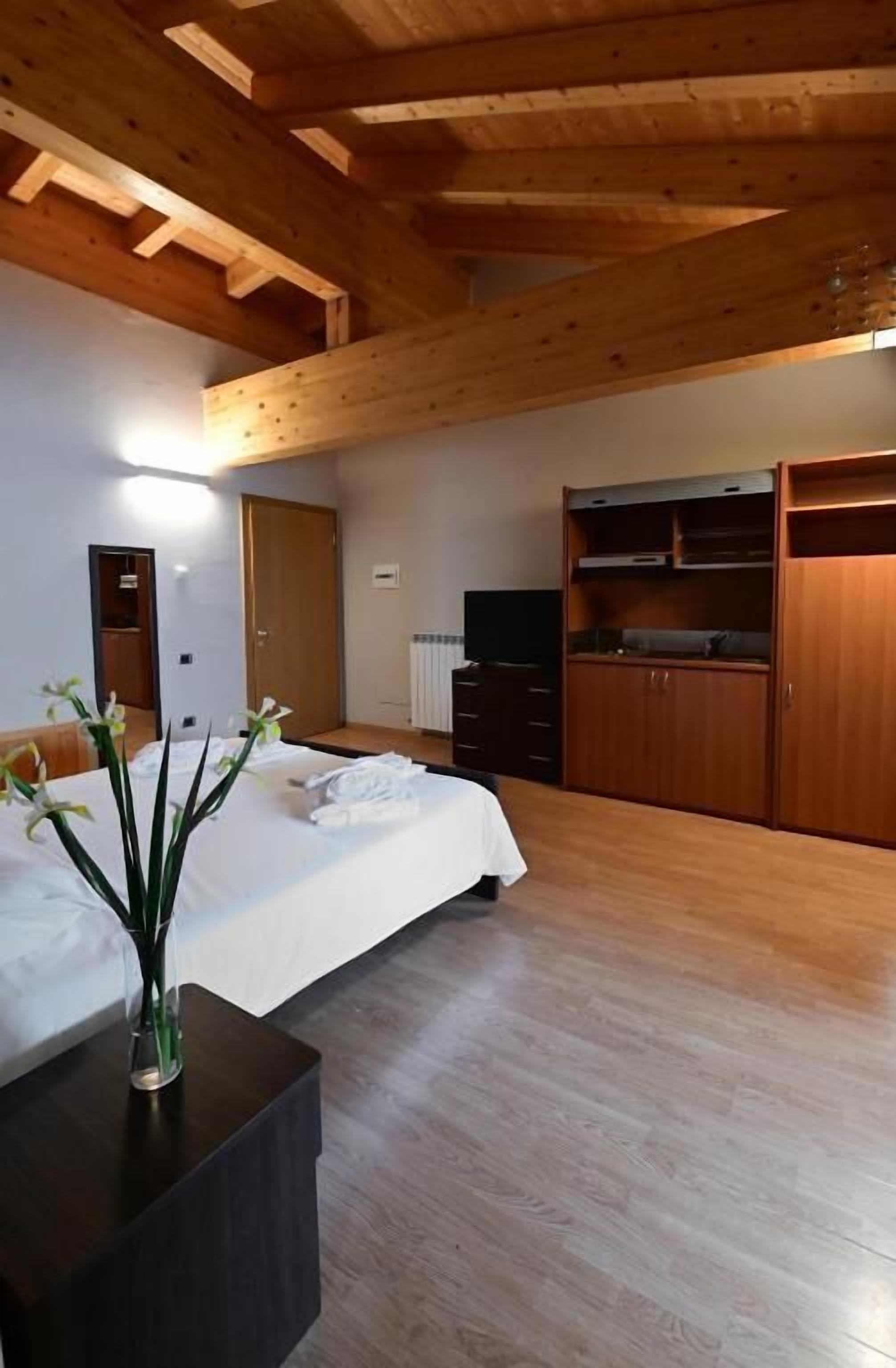 Une chambre à coucher comprenant un lit, une table de chevet, une armoire et un téléviseur encastré.