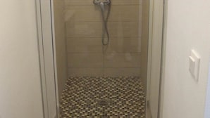 A glass-enclosed shower stall with a tiled floor and a showerhead. - FAMILY STUDIO (Saint-Côme-de-Fresné)