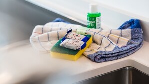 Ein Spülbecken mit einem Lappen, einem Schwamm und Reinigungsspray.