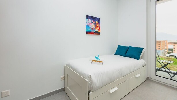 Ein Schlafzimmer mit einem Bett, einem Fenster und einem Bild an der Wand.