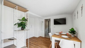 Ein stilvoller Essbereich mit Holztisch, weißen Stühlen und einer Topfpflanze.