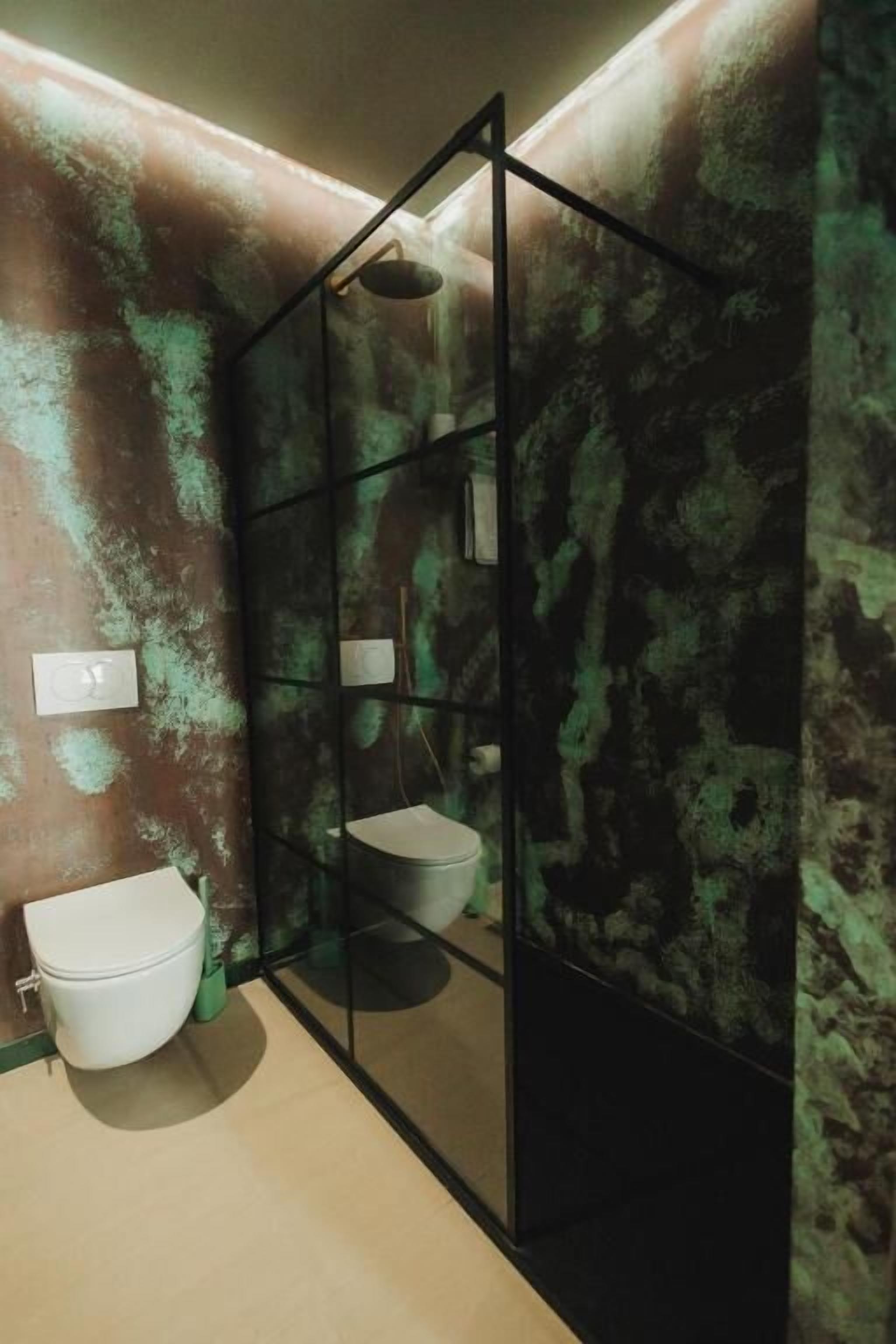 Ein Badezimmer mit modernem Design, ausgestattet mit einer Glasabtrennung, einer Duschkabine und zwei Toiletten.