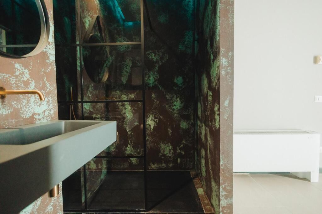 A bathroom with a modern sink, a shower area, and a white bench.