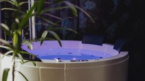 A spa area with a hot tub, a potted plant, and a dark wall with a textured pattern.