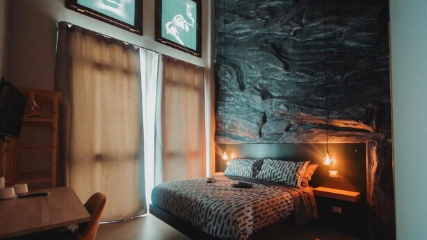 A bedroom with a bed, bedside table, and a wall with a textured design.