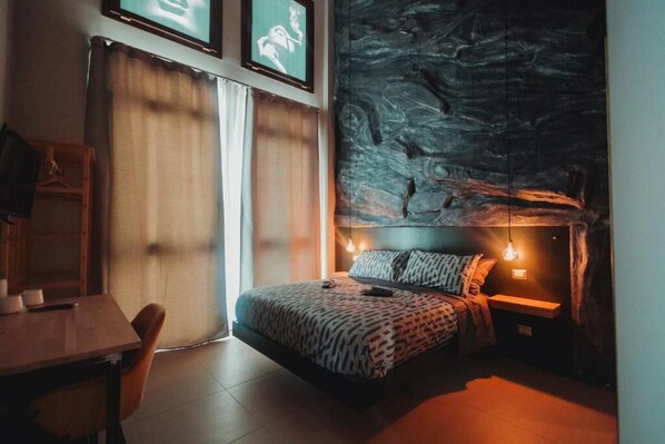 A bedroom with a bed, bedside table, and a wall with a textured design.