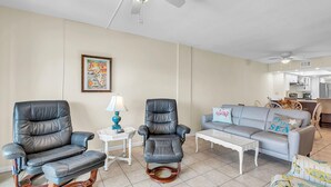 A living room with a black leather chair, a grey sofa, a white coffee table, and a ceiling fan. - Shalimar 302 (Indian Rocks Beach)