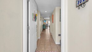 A hallway with a tiled floor, a door on the left, and a number sign on the right. - Shalimar 302 (Indian Rocks Beach)