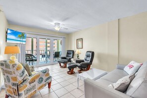 A living room with a sofa, two armchairs, a coffee table, a TV, and a ceiling fan. - Shalimar 302 (Indian Rocks Beach)