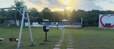 Un parque con un columpio, un cartel con forma de corazón y un sendero pavimentado.