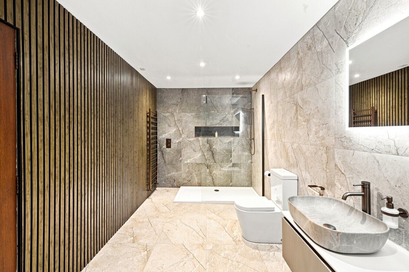Ein modernes Badezimmer mit einer großzügigen Badewanne, einer freistehenden Toilette und einem Aufsatzwaschbecken.