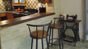 Una cocina con gabinetes de madera, estufa y taburetes de bar.
