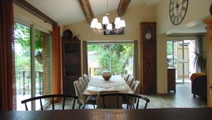 Comedor con una mesa grande, sillas, una lámpara de araña, un reloj y vistas al exterior.