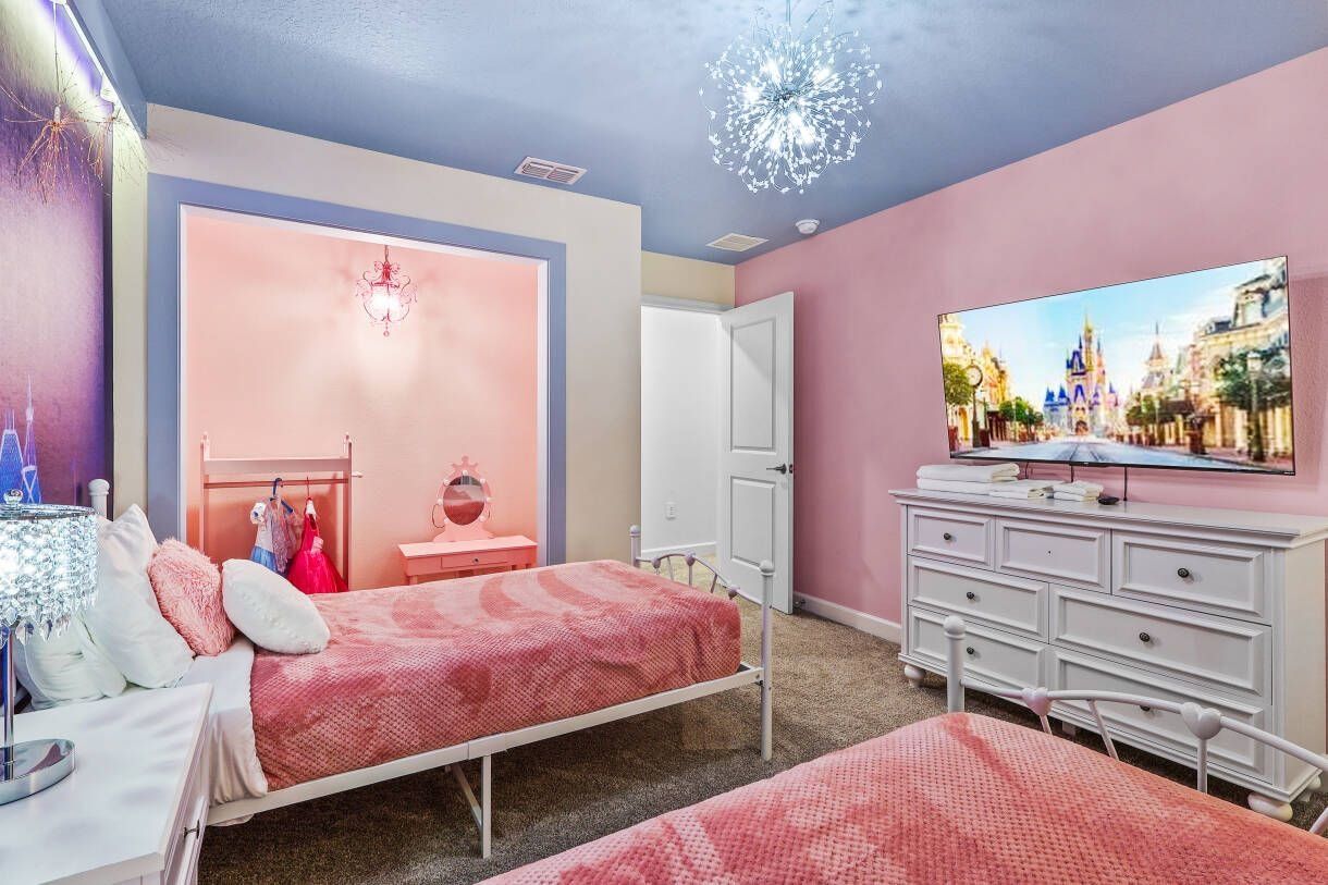 Un dormitorio con cama, cómoda, televisor y puerta que da a otra habitación.