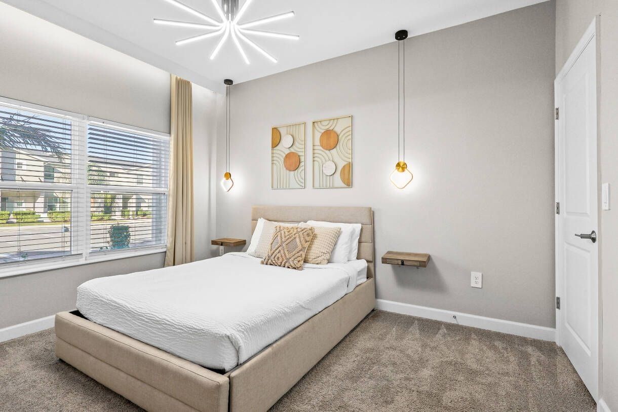A bedroom with a bed, bedside tables, a ceiling light fixture, and artwork on the wall.