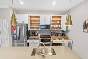 A modern kitchen with white cabinets, stainless steel appliances, and pendant lighting. - 4BR Storey Lake Home Near Disney With Pool (Kissimmee)