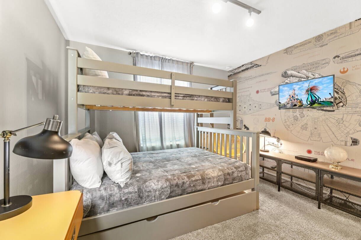 A bunk bed with a desk and a TV in a room with a map-themed wall.
