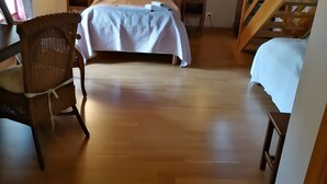 A bedroom with a bed, a chair, a nightstand, a lamp, and a wooden staircase.