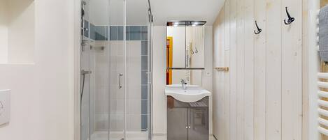 A modern bathroom with a glass-enclosed shower, a sink, and a mirror.