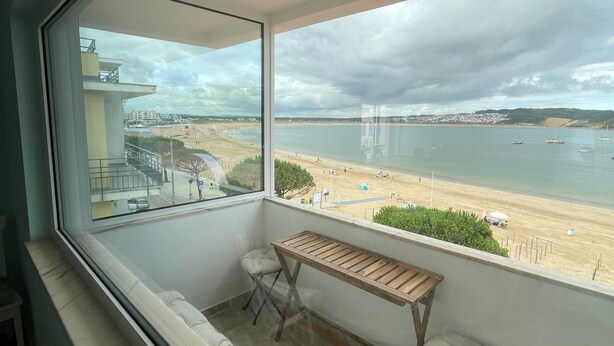 A balcony with a view of the beach, a small table, and two chairs. - Duplex Apartment with Panoramic Views of the Beach at São Martinho do Porto (São Martinho do Porto)