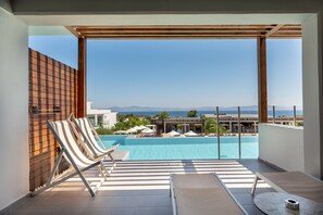 Un balcon avec une piscine, des chaises longues et une vue sur la mer.