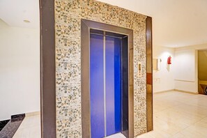 An elevator with a blue interior, surrounded by a speckled wall and a brown frame. - Classic Amritsar City Centre (Amritsar)