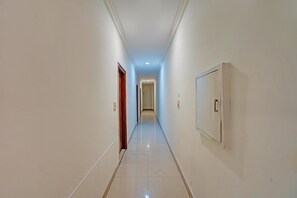 A corridor with white walls, a tiled floor, and doors on both sides. - Classic Amritsar City Centre (Amritsar)