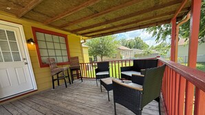 Un porche cubierto con muebles de exterior, una puerta y una ventana con persianas.