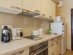 Een kitchenette met een koffiezetapparaat, toaster, waterkoker, magnetron en een koelkast.
