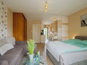 Een hotelkamer met een bank, een bed, een eettafel en een keukenhoek.