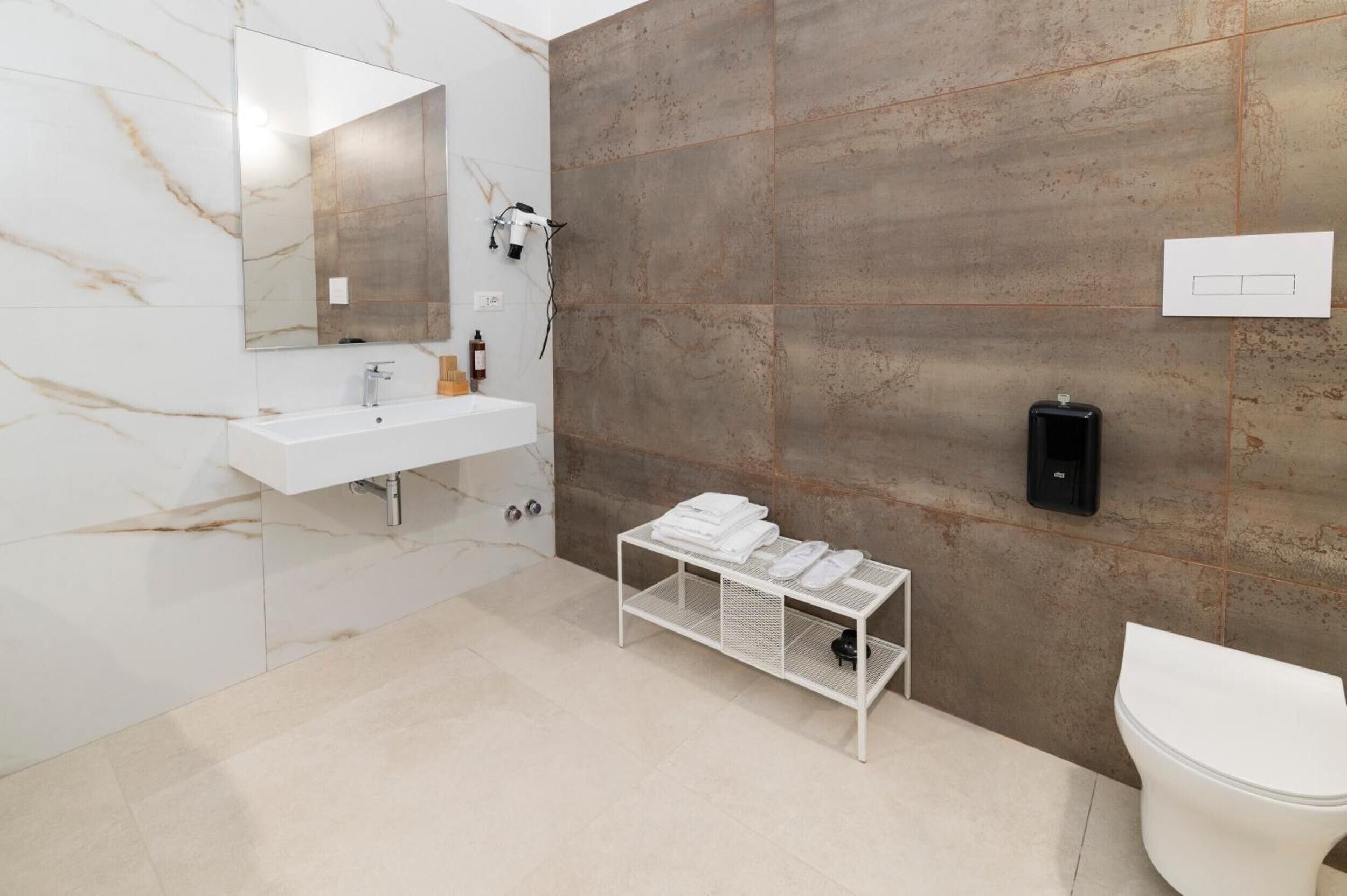 A modern bathroom with a white sink, a mirror, a towel rack, and a toilet.