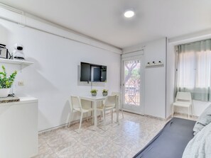 A clean, modern room with a bed, a desk with a chair, a TV mounted on the wall, and a door leading outside. - Apartment Cannes by Interhome (Playa de Aro)