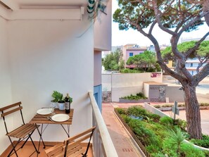 Un balcón con una mesa para dos, una botella de vino y plantas en macetas.