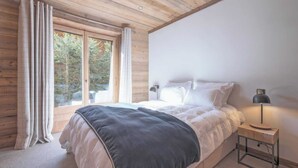 A bedroom with a bed, a nightstand, a lamp, and a window with curtains. - Exceptional Chalet With Pool A/C 10P - Megeve (Megeve)