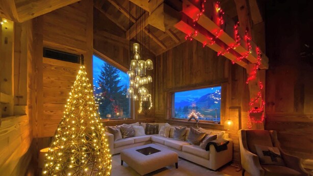 A cozy cabin interior with a large window, a white sofa, a small table, and a Christmas tree. - Exceptional Chalet With Pool A/C 10P - Megeve (Megeve)