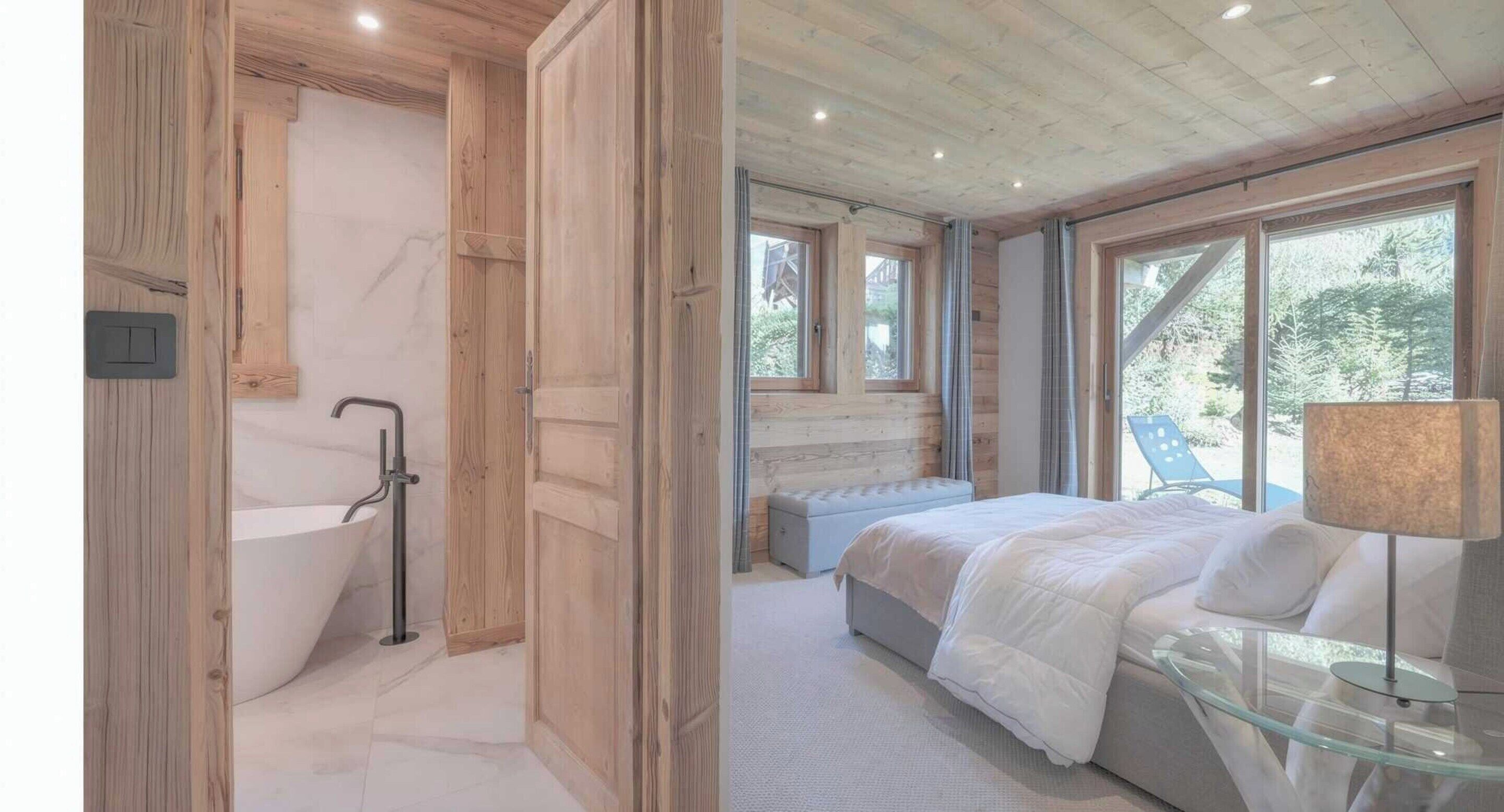A modern bedroom with a large window, a bathtub, and a glass table.