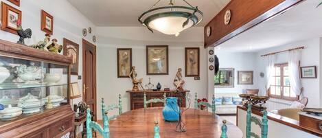 A dining room with a wooden table, turquoise chairs, and a chandelier.