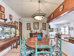 Une salle à manger avec une table en bois, des chaises turquoise et un lustre.