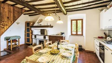 Una cucina rustica con un tavolo da pranzo per quattro persone, travi in legno al soffitto e una finestra vista sul verde.