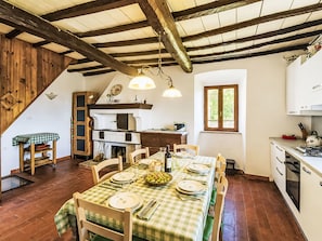Una cucina rustica con un tavolo da pranzo per quattro persone, travi in legno al soffitto e una finestra vista sul verde.