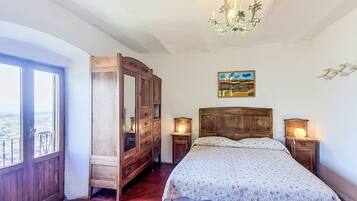 Una camera da letto con un letto grande, un'armadio in legno, abat-jour, un lampadario e un quadro appeso al muro.